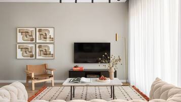 Una sala de estar moderna con una televisión de pantalla plana, un sofá, una mesa de centro y una silla.