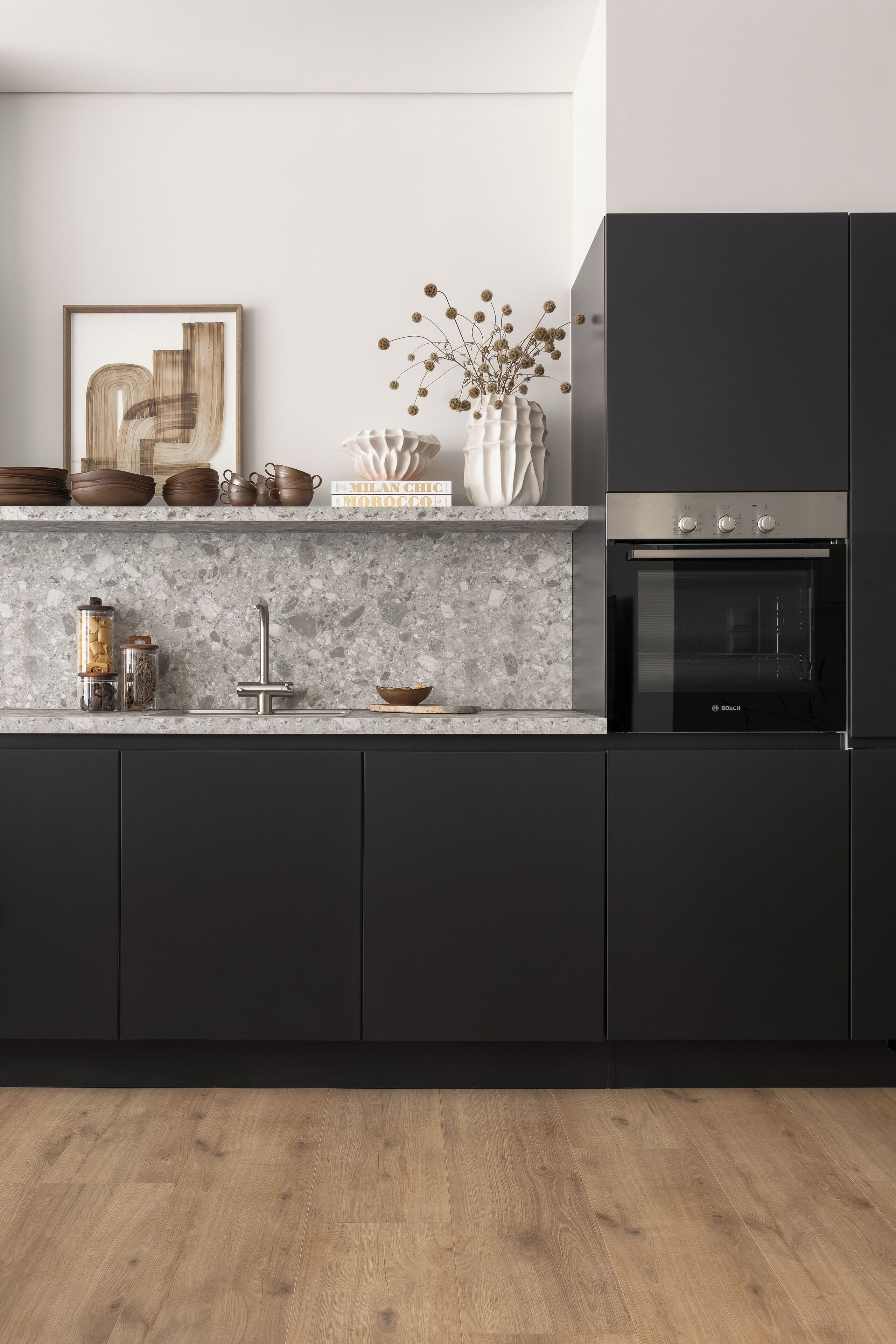 A modern kitchen with dark cabinetry, a marble countertop, and a Bosch oven.