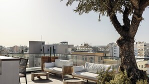 Una terrazza sul tetto con posti a sedere all'aperto, un albero grande e vista sulla città.