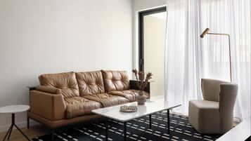 A modern living room with a brown leather sofa, a white coffee table, a side table, and a floor lamp.