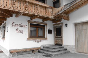 A building with a wooden balcony, a window with a wooden frame, and a door.