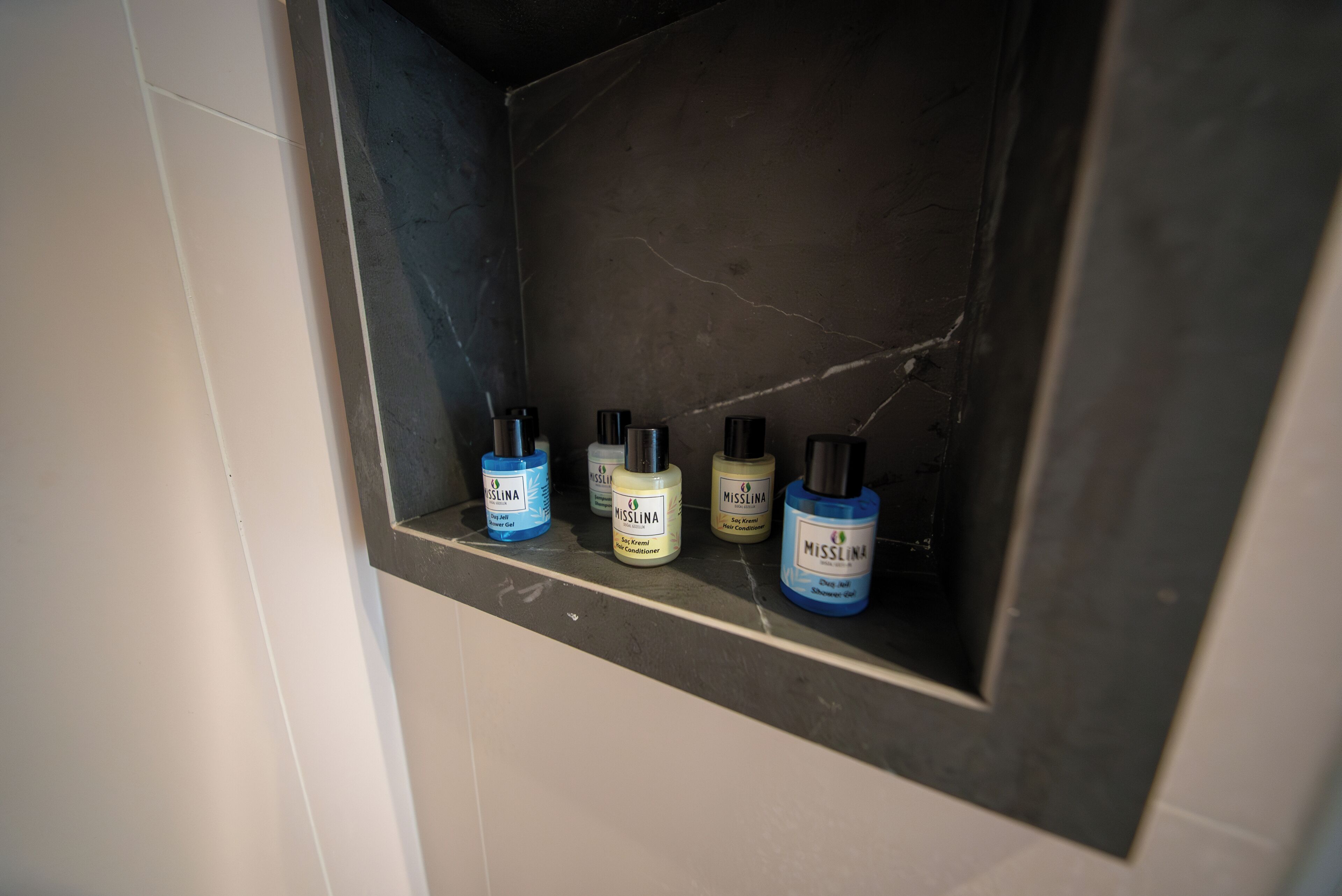 Un estante en el baño con cuatro botellas de productos Misslina.