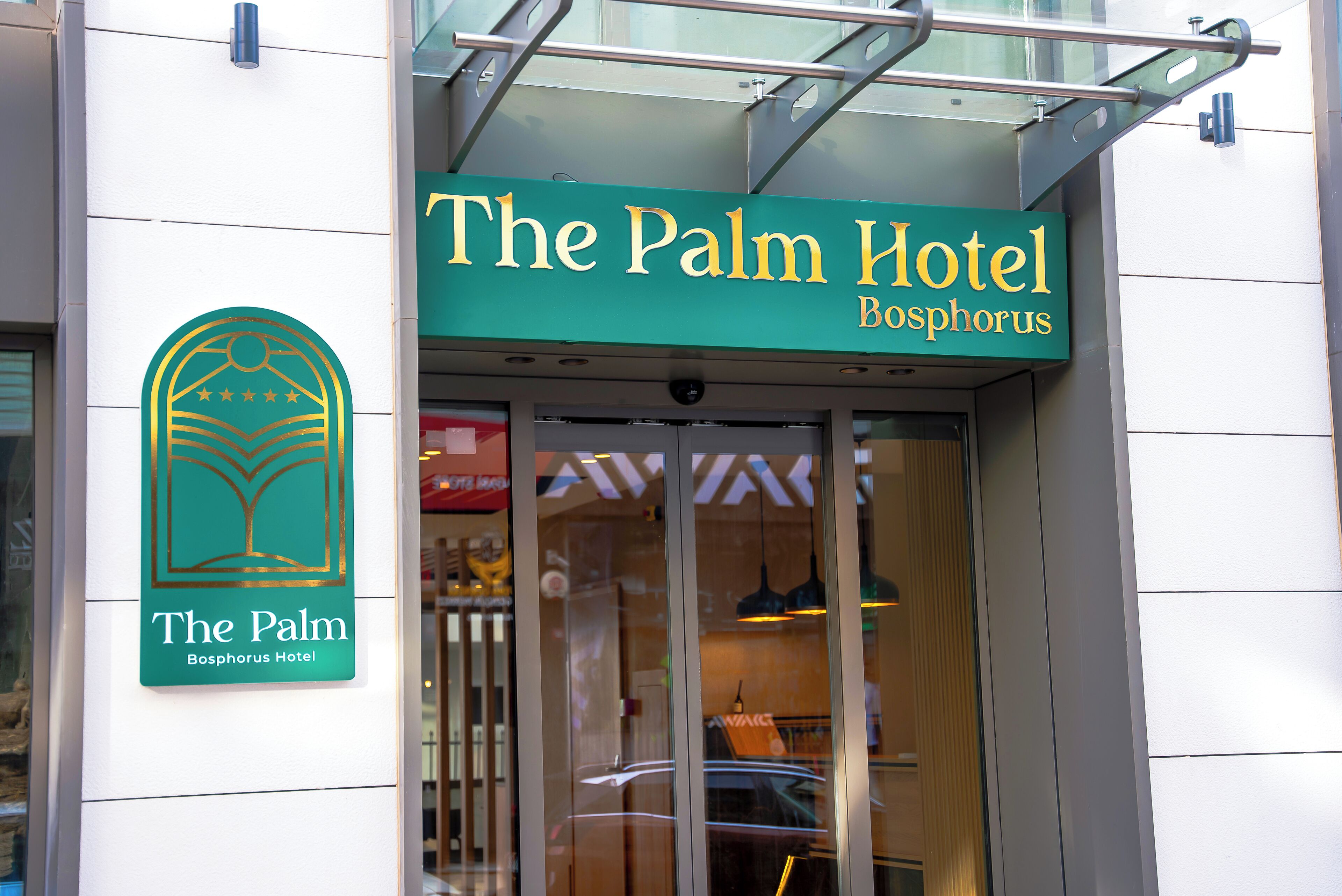 Enseigne de l’hôtel Palm Bosphorus, avec son logo, son entrée et ses portes en verre.