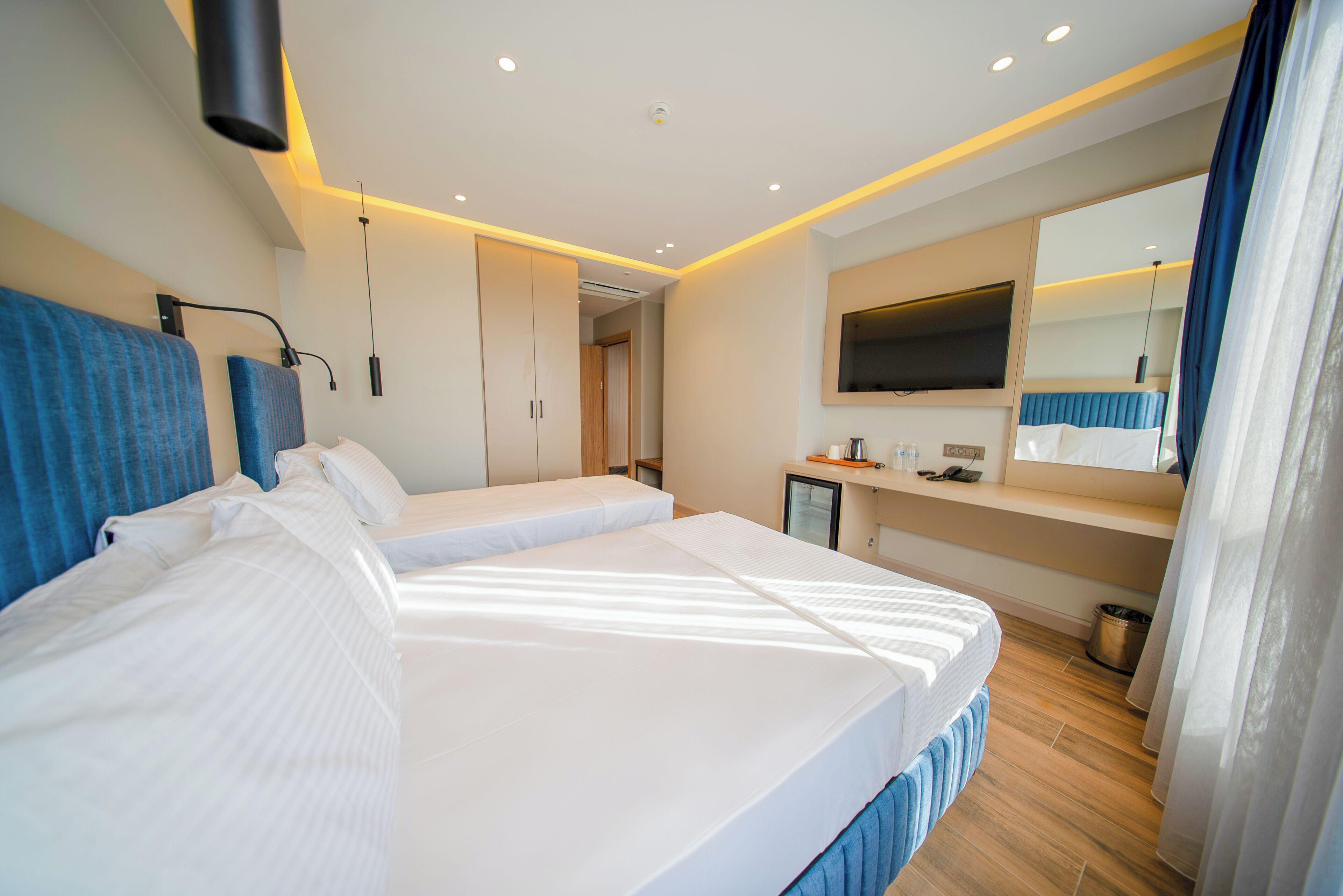 Une chambre d’hôtel moderne, dotée d’un grand lit, de tables de chevet, d’une télévision et d’une salle de bain.