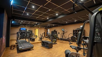 A gym with various exercise equipment, including treadmills, elliptical machines, and weight machines.
