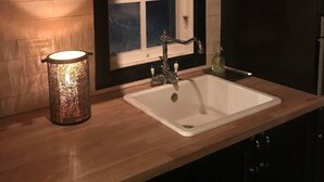 A kitchen with a white sink, a window with a white frame, and a decorative candle holder.