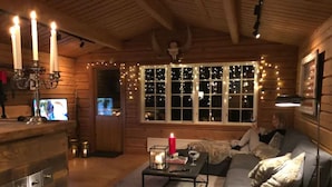 A cozy cabin interior with wooden walls, a sofa, a coffee table, and a TV.