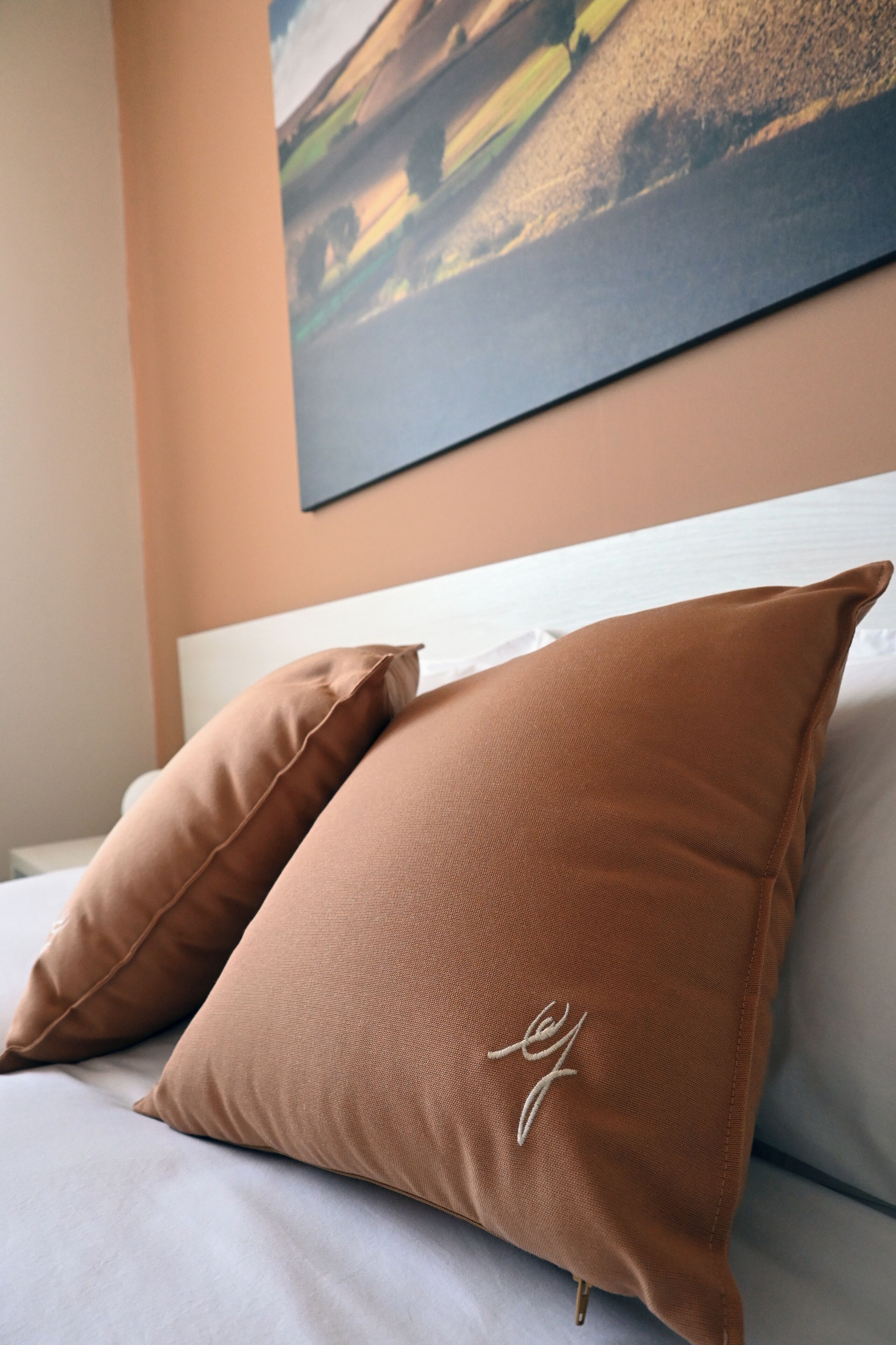 Una cama con dos almohadas marrones y un cabecero blanco.