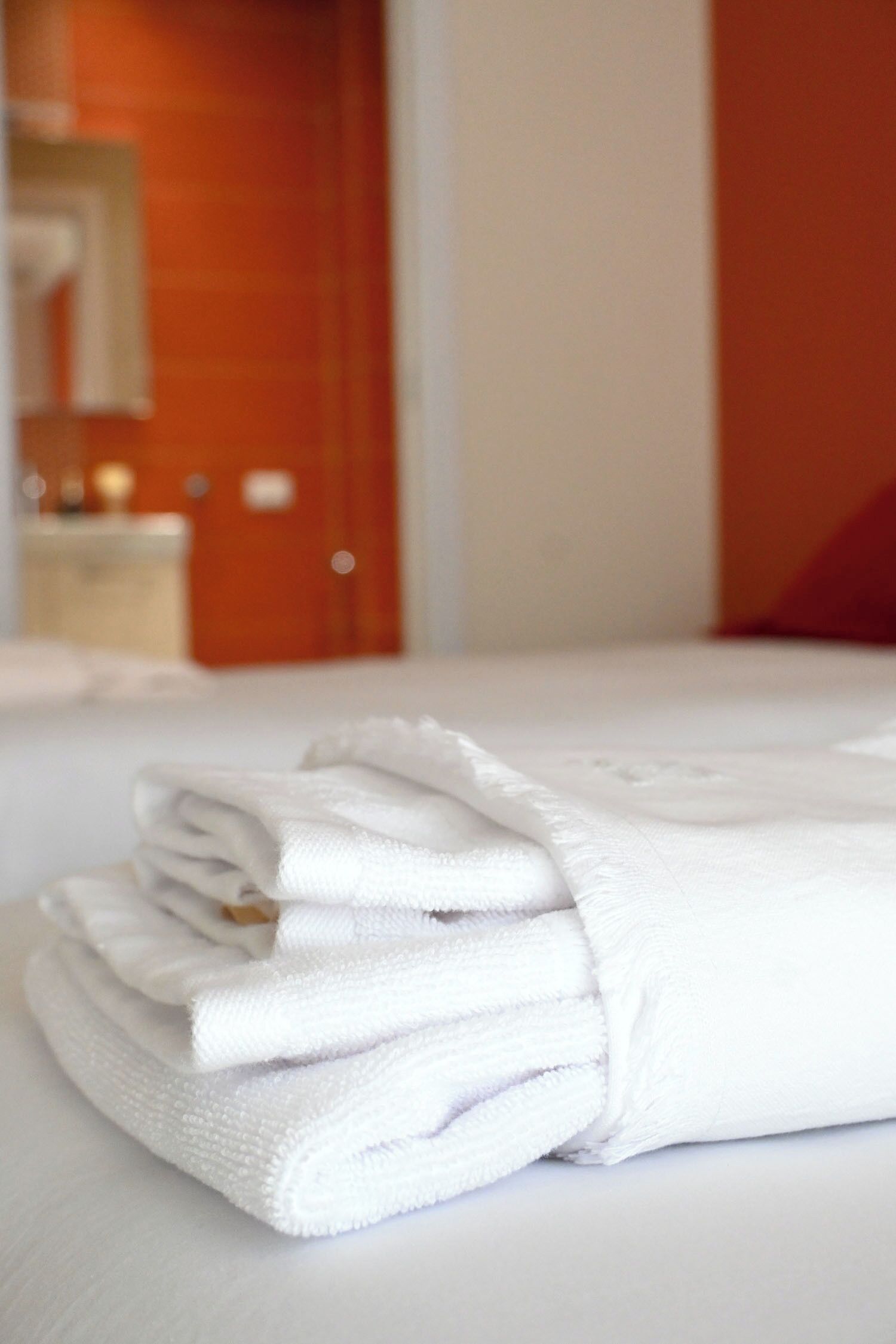 Un montón de toallas blancas ordenadas sobre una cama en una habitación de hotel.