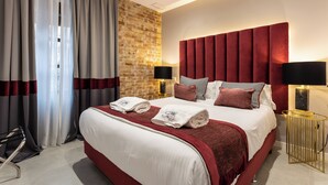 A hotel room with a large bed, red headboard, and two bedside lamps. - BIBO SUITES PLAZA NUEVA (Granada)
