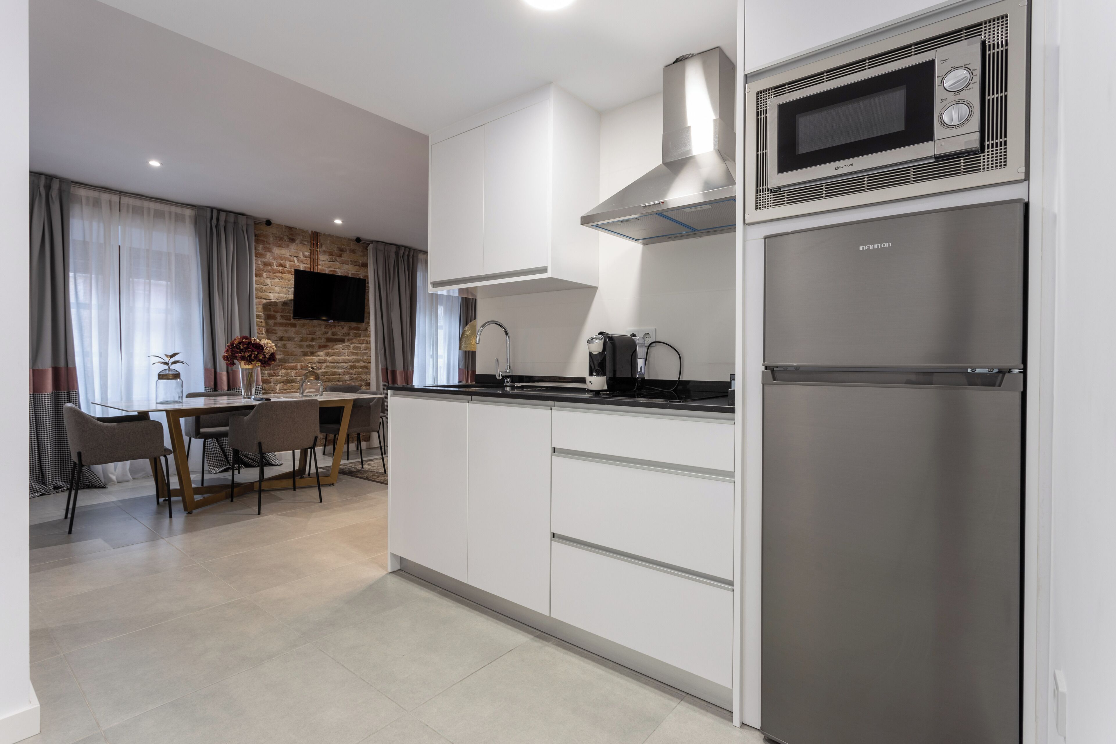 A modern kitchen with white cabinetry, a stainless steel refrigerator, a built-in microwave, and a gas stove.