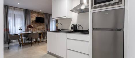 A modern kitchen with white cabinetry, a stainless steel refrigerator, a built-in microwave, and a gas stove.