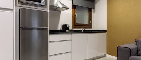 A compact kitchen with a built-in microwave, oven, and gas stove. There is a window with a blind, a sink, and a small countertop area.