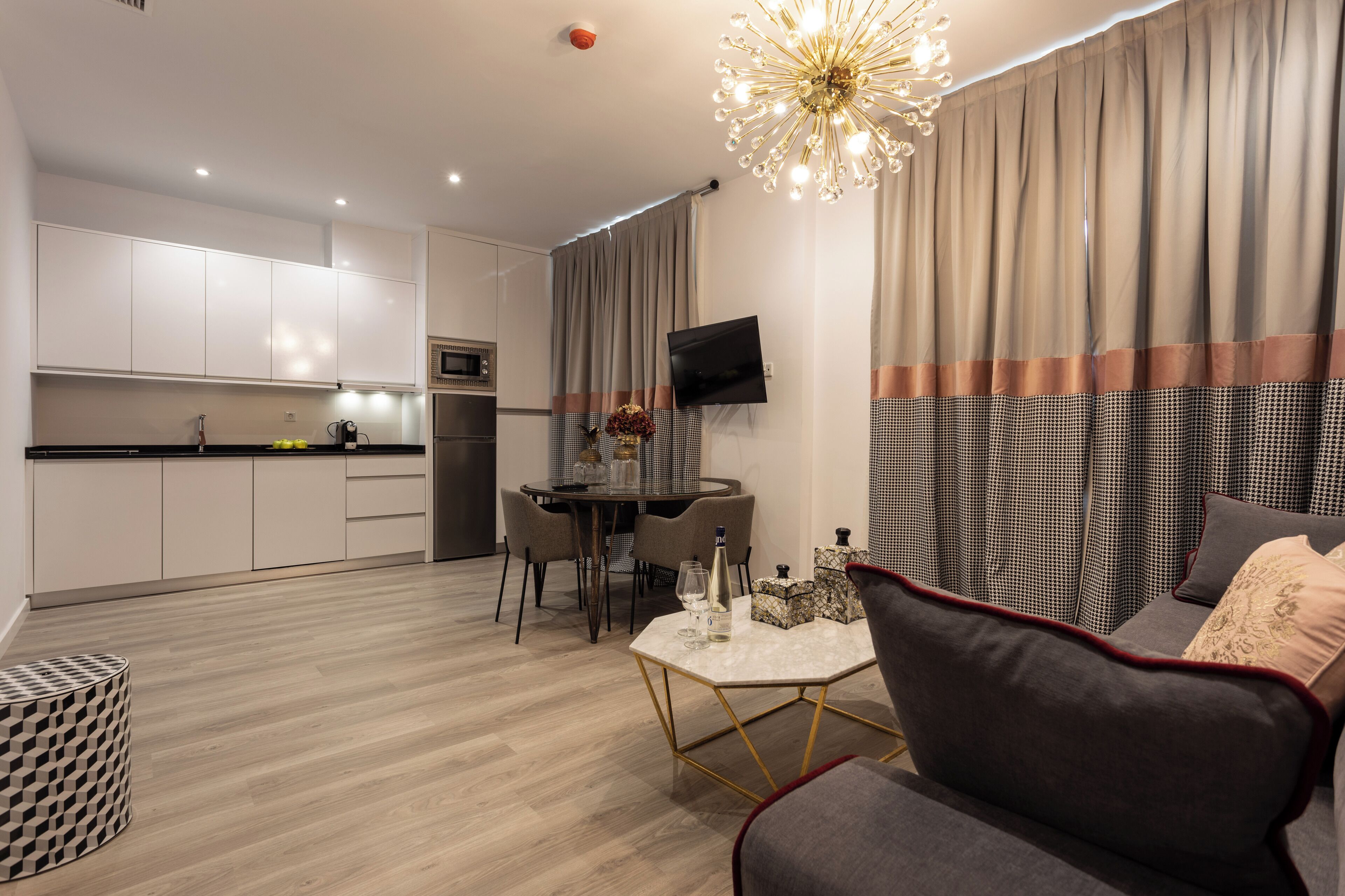 Een moderne woonkamer met een grijze bank, een salontafel, en een eetgedeelte met een ronde tafel en stoelen.