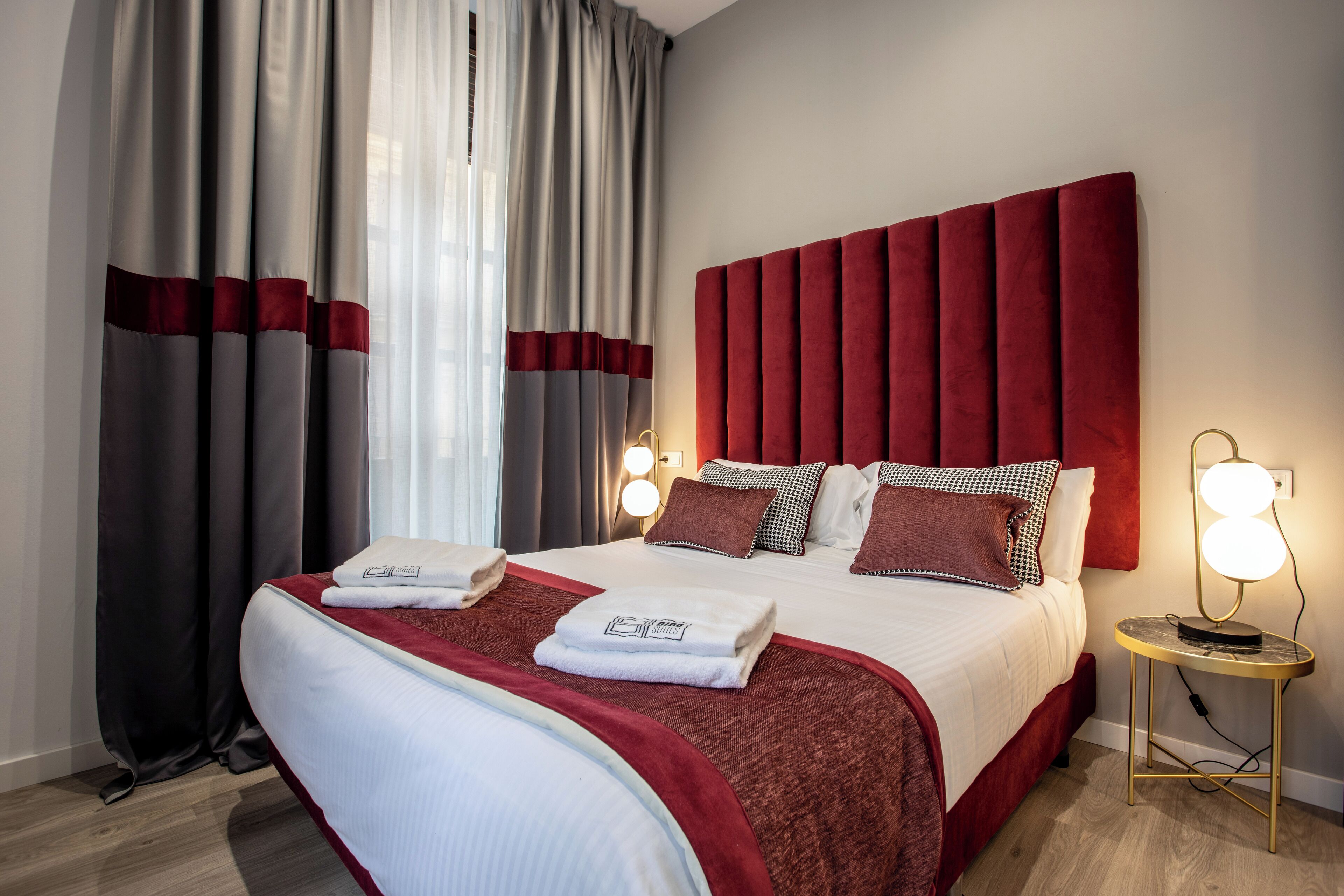 Ein Hotelzimmer mit einem großen Bett, einem roten Kopfteil und zwei Nachttischlampen.