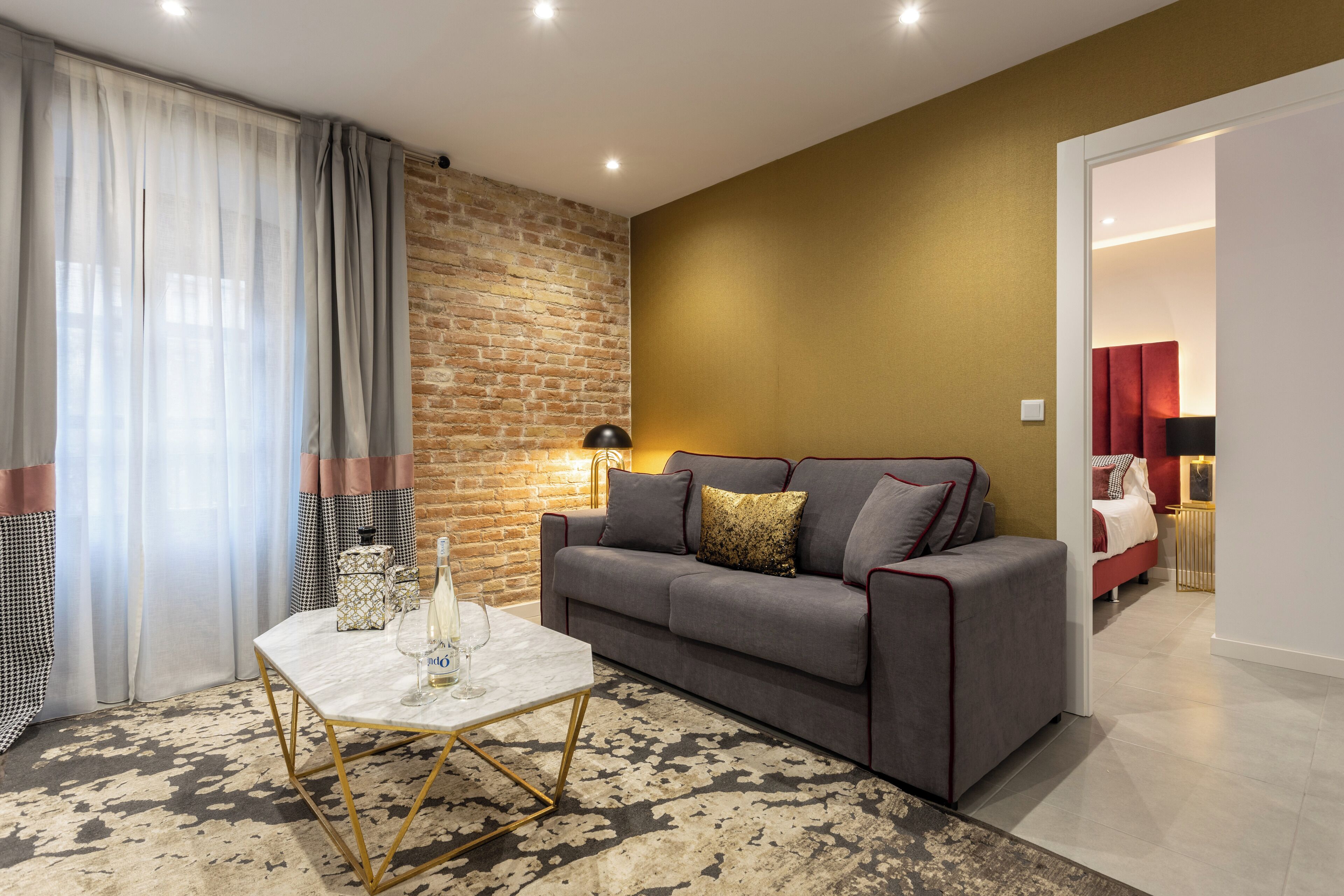 Ein modernes Wohnzimmer mit einem grauen Sofa, einem Marmortisch und einem gemusterten Teppich.