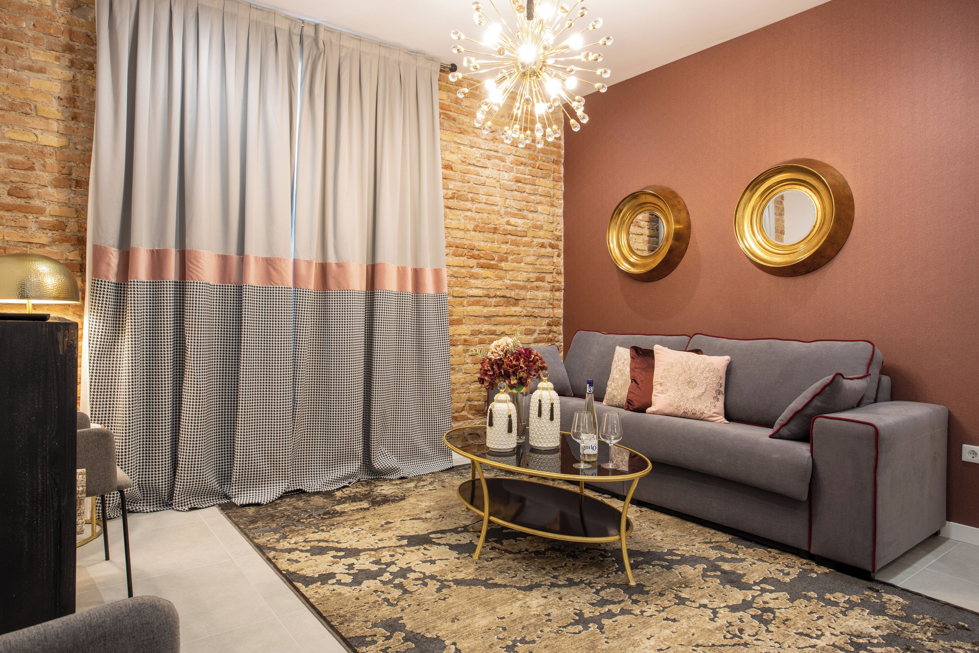 Un soggiorno con un divano grigio, un tavolino rotondo e un tappeto decorato.
