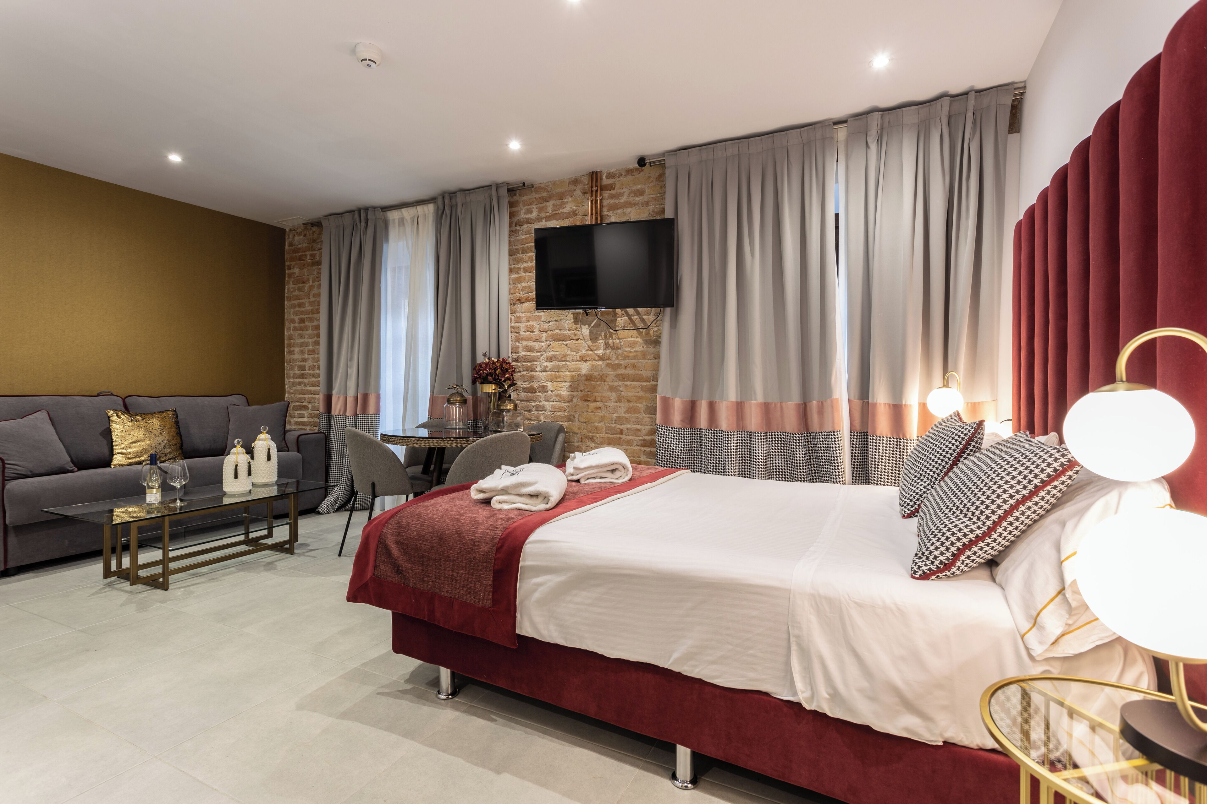 Una habitación de hotel moderna con una cama grande, un sofá, una mesa de centro y un televisor montado en la pared.