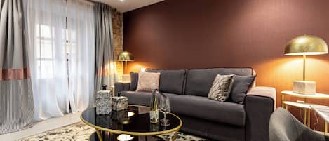 A modern living room with a dark grey sofa, a round black coffee table, and a patterned rug.