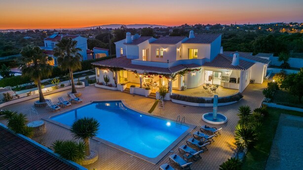 Una villa moderna con piscina, mobiliario exterior y un jardín ajardinado.