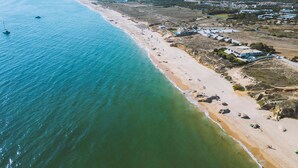 Vista aérea de una zona costera con playa, puerto deportivo y edificios residenciales.