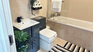 Ein modernes Badezimmer mit Duschkabine aus Glas, einem weißen Waschbecken und einer Toilette.
