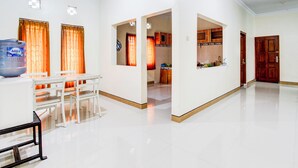 A spacious living area with a dining table and chairs, a kitchen visible through an archway, and a large water dispenser. - Hotel O Homestay Putra Syariah (Kasihan)