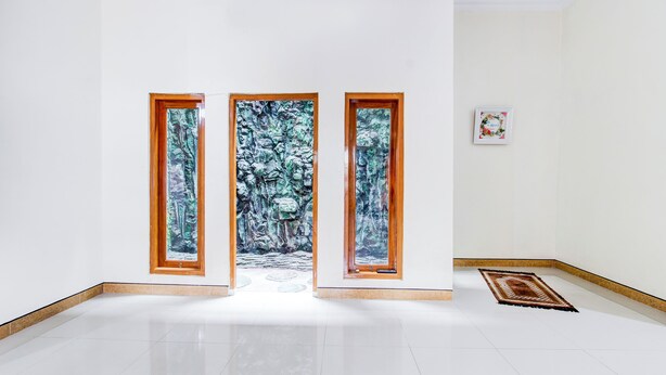 A hallway with three wooden-framed windows leading to a forest scene. - Hotel O Homestay Putra Syariah (Kasihan)