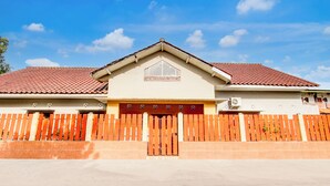 A house with a red-tiled roof, a wooden fence, and a gated entrance. - Hotel O Homestay Putra Syariah (Kasihan)