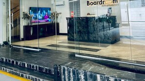Ett modernt receptionsområde med en glasvägg, en receptionsdisk och en skylt med texten ”Boardroom Apartments”.