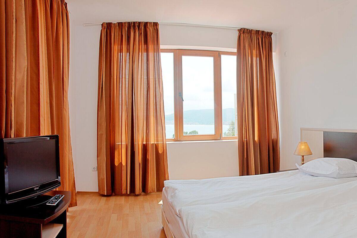 A hotel room with a bed, a TV, and curtains.