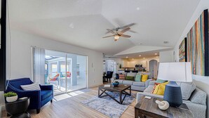 A spacious living area with a ceiling fan, a sofa set, a coffee table, and a view through a glass door to the outside. - ⭐NEWLY REFURBISHED | 4 Bed Villa | Large Private Pool Deck | Minutes to Disney⭐ (Davenport)