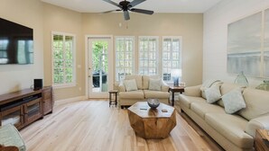 A spacious living room with a beige sofa, a wooden coffee table, and a ceiling fan.