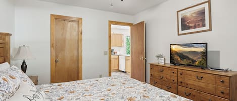 Ein Schlafzimmer mit einem Bett, einem Schminktisch, einem Fernseher und einem Deckenventilator.