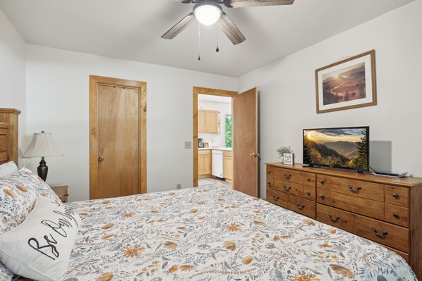 A bedroom with a bed, a dresser, a television, and a ceiling fan. - Cosy Cabin|King Suite main floor|Game Room|Hot Tub (Gatlinburg)