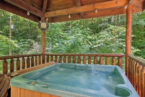 Een houten kuipjacuzzi met uitzicht op een bos.