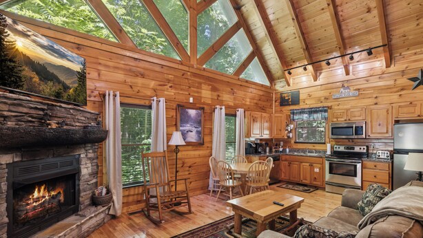 Ein Ferienhaus-Interieur mit Kamin aus Naturstein, Esstisch aus Holz und Küchenzeile.