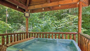 Ein hölzernes Whirlpool mit Holzterrasse und Geländer, umgeben von üppigem Grün.