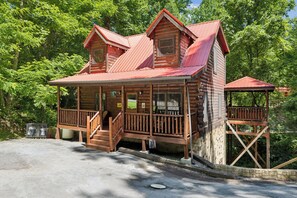 Une cabane en bois dotée d’un porche, d’une terrasse couverte et de fondations en pierre.