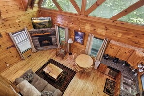 L’intérieur d’une cabane est agrémenté d’une cheminée en pierre, de meubles en bois, d’un coin repas et d’une cuisine dotée de plans de travail en granit.