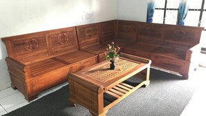 Een houten zitmeubelset met ingewikkelde houtsnijwerken, een bijpassende houten salontafel en een kleine potplant.
