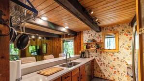 A kitchen with wooden cabinets, a countertop, a sink, and hanging pots. - Woodland Lodge - Perfect Family Ski Chalet! Close to Nubs Nob & Boyne! (Harbor Springs)