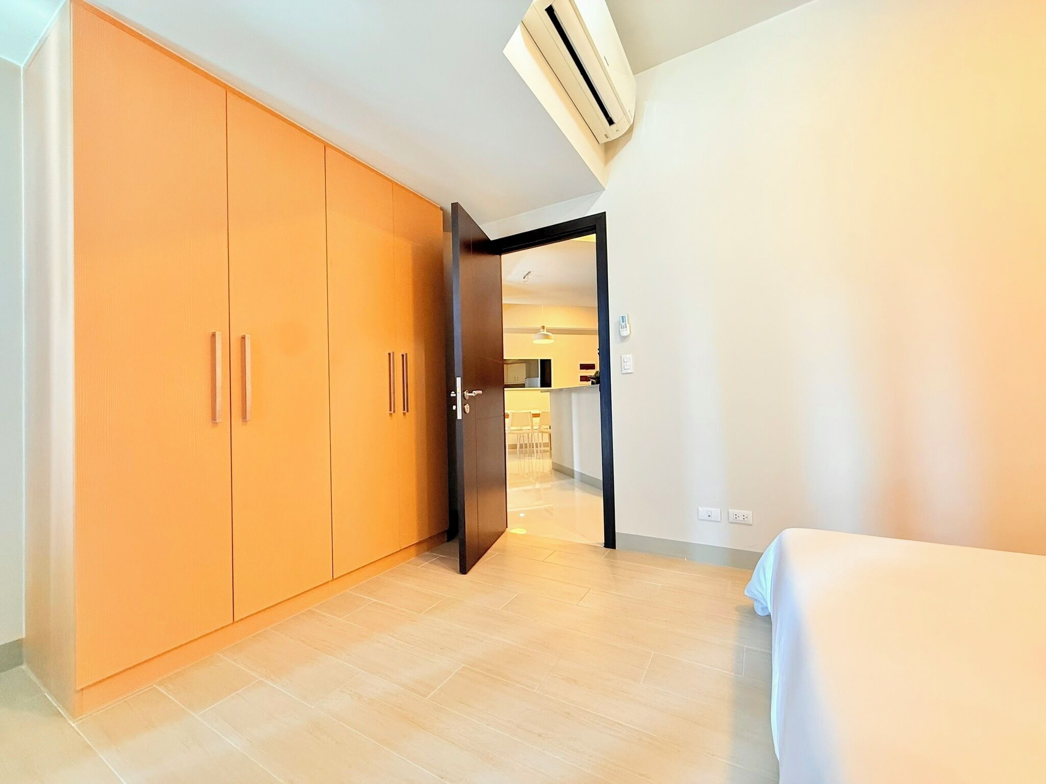 A hotel room with a large wardrobe, a bed, and an air conditioning unit.