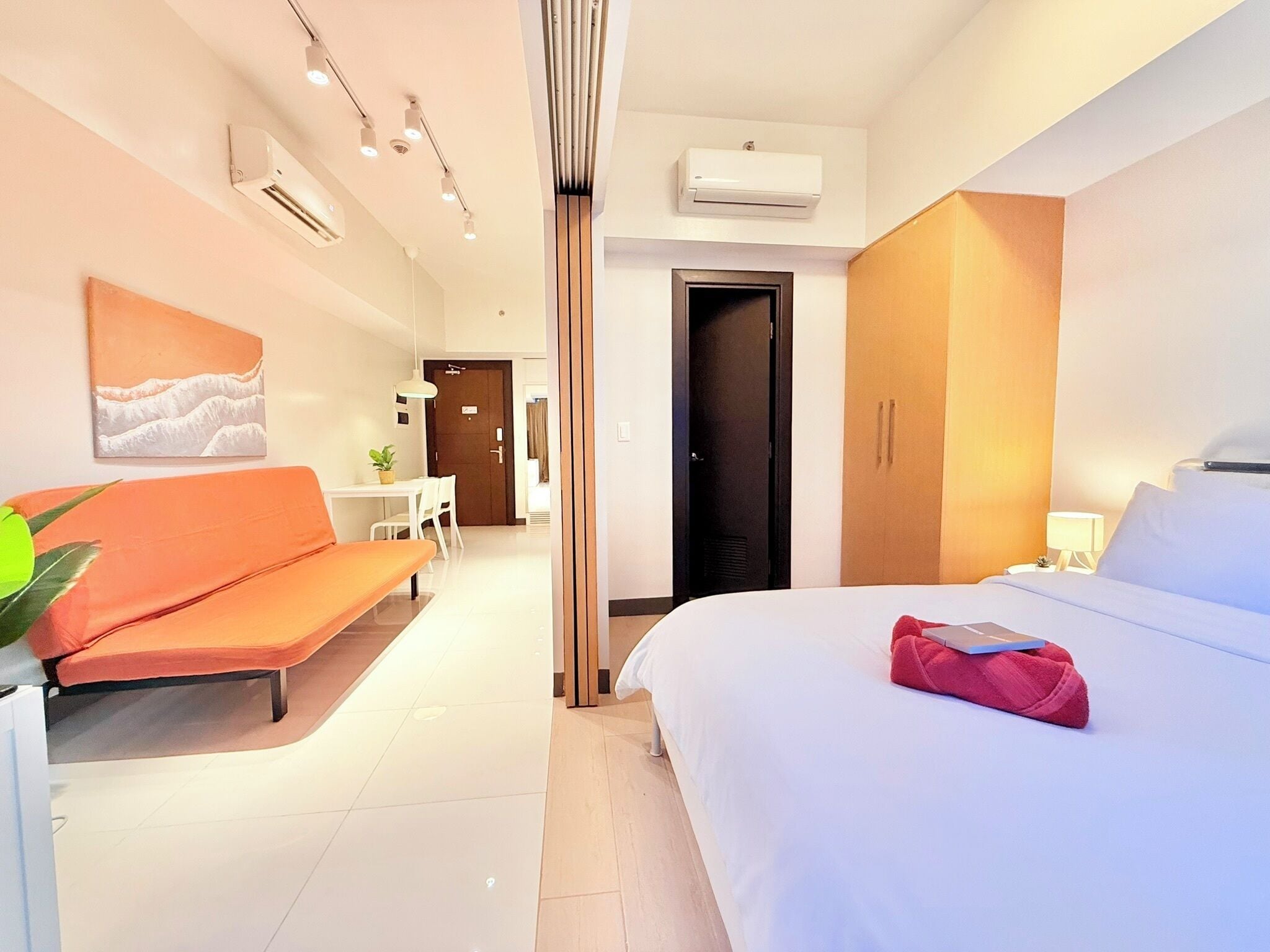 Une chambre d’hôtel moderne équipée d’un lit, d’un canapé, d’un bureau et d’un appareil de climatisation.