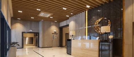 A modern lobby with a reception desk, wooden ceiling, and a large mirror.