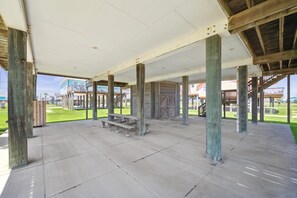 An outdoor covered area with concrete flooring, wooden pillars, and a bench. - Surfside Retreat - Great Views & Steps from Beach (Freeport)