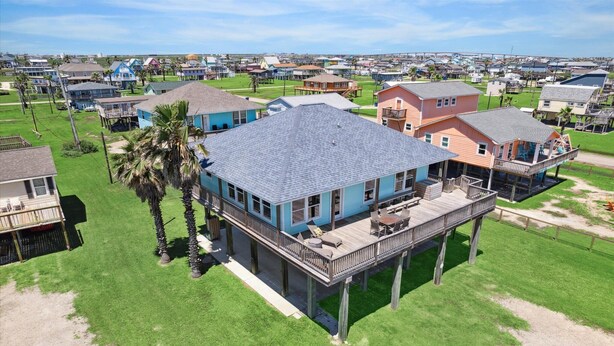 A coastal house with a deck, surrounded by other houses and a beach in the background. - Surfside Retreat - Great Views & Steps from Beach (Freeport)