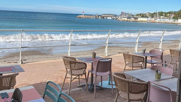 An outdoor seating area with tables and chairs overlooking the ocean. - A little corner of Paradise - 4 minutes walk to the beach and restaurants (Saint-Cyr-sur-Mer)
