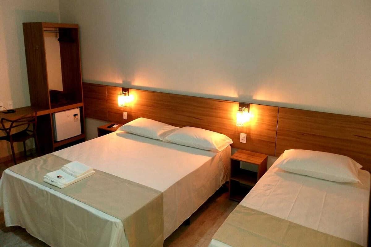 Habitació d'hotel amb dos llits, un escriptori i un armari.