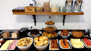 A buffet table with various food items, including pastries, fruits, and a cake.
